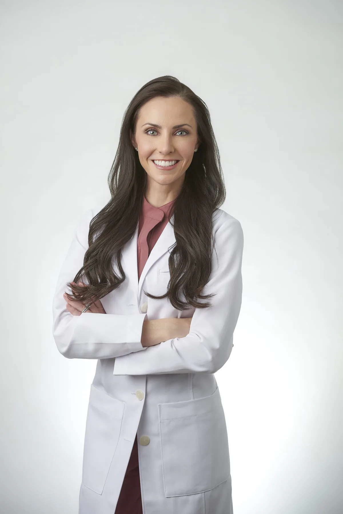 Dr. Ashley Howarth, board-certified plastic surgeon, in a white lab coat